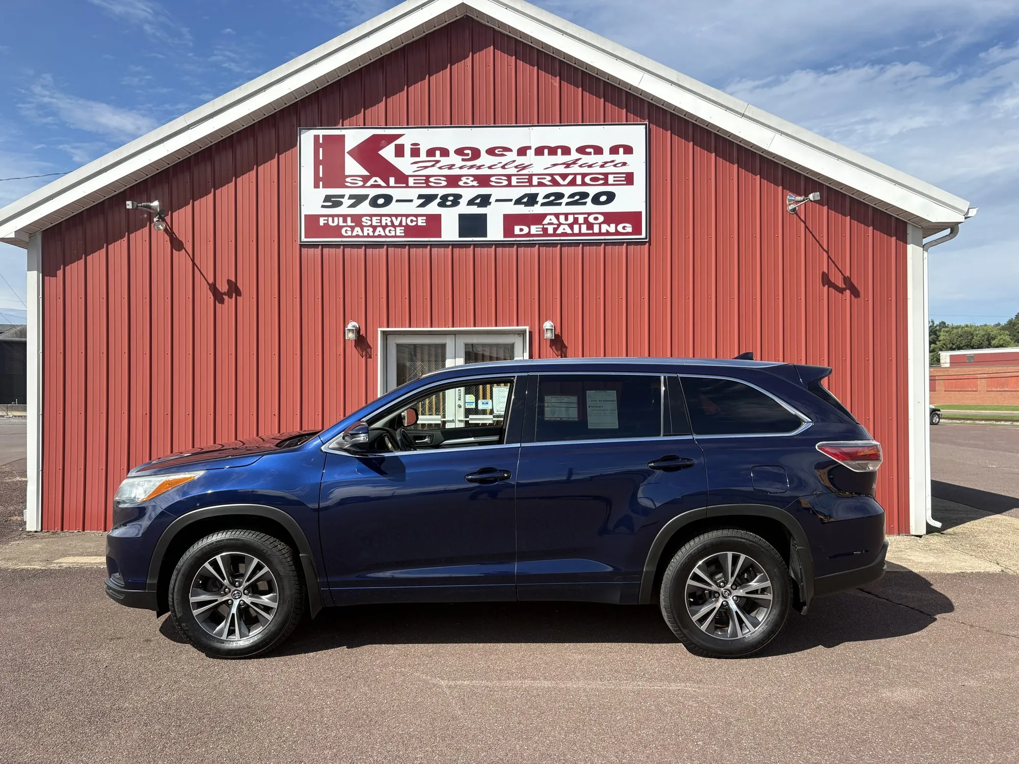 A dark blue 2016 Toyota Highlander XLE parked in front of the Klingerman Family Auto building